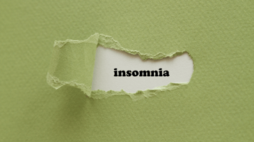 A piece of green paper with a small piece torn away to reveal the word insomnia.