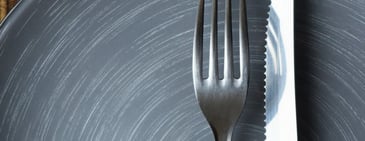 A closeup of a metal fork against a textured gray background. 
