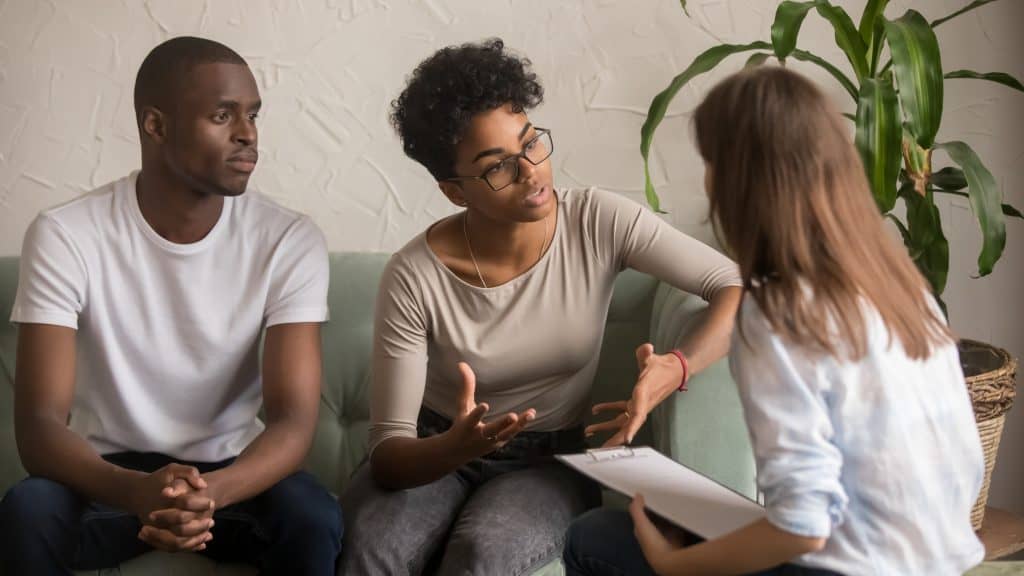 A couple meets with a co-parenting counselor at their office.