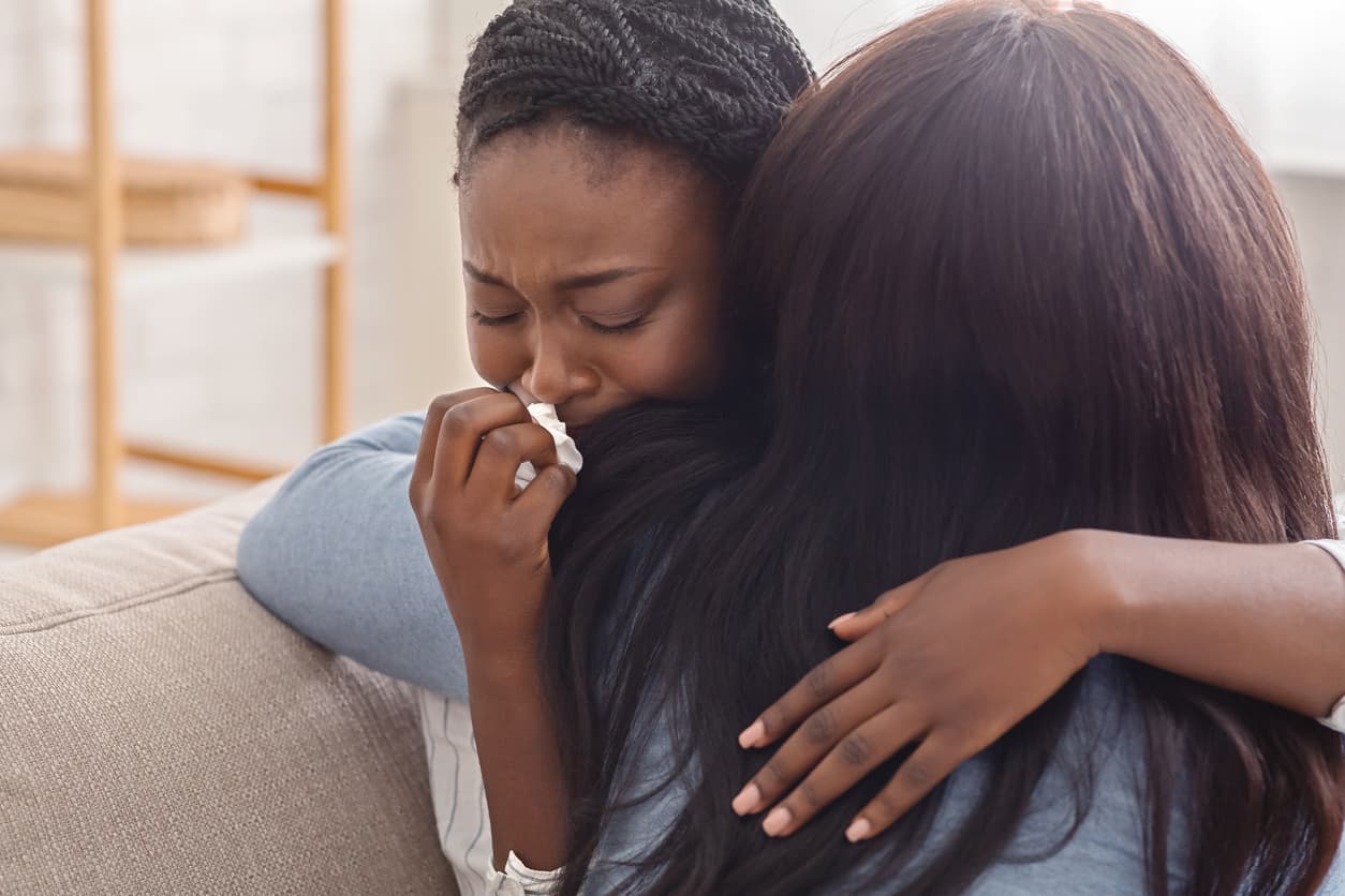 Woman hugging her crying girlfriend, supporting her after receiving bad news.