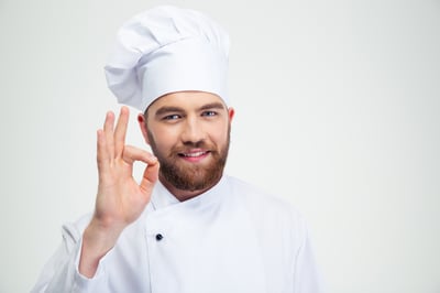 Portrait of a smiling male chef cook showing ok sign isolated on a white background