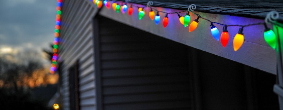 Multicolored holiday lights on the eaves of a home at dusk. 
