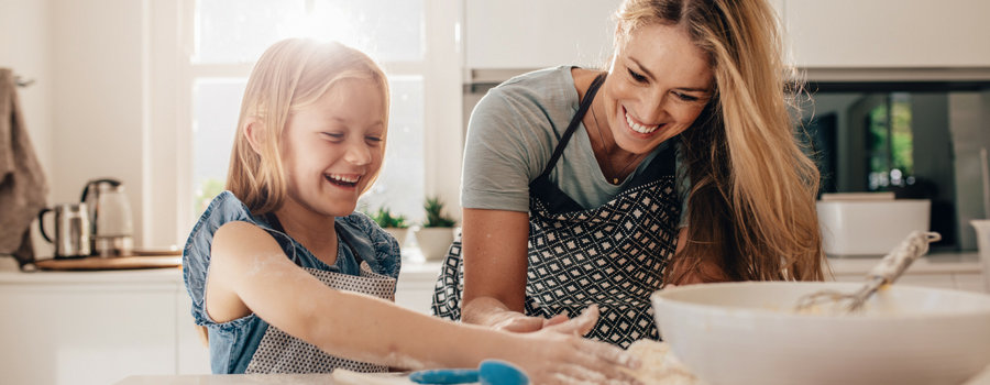 A mother and child baking together in a home kitchen. 